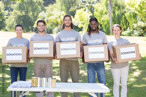 Happy volunteers with donation boxes in park