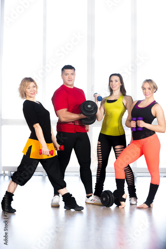 Group of sporty people holding dumbbells in gym