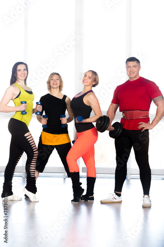 Fototapeta Naklejka Na Ścianę i Meble -  Group of positive sporty bodybuilders doing weight training in g