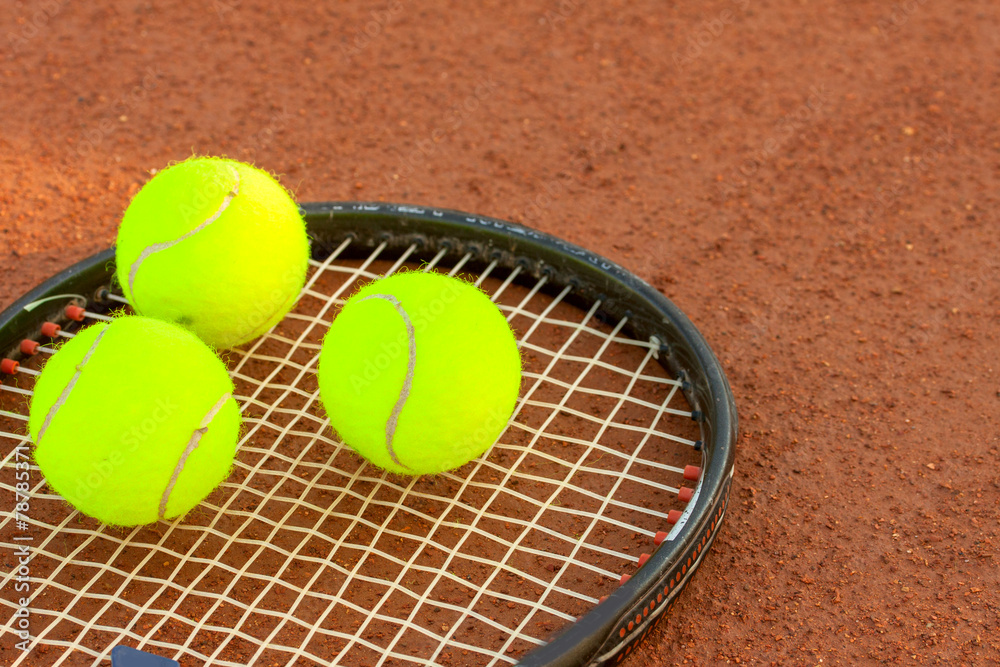 Tennis ball and racquet on a tennis clay court