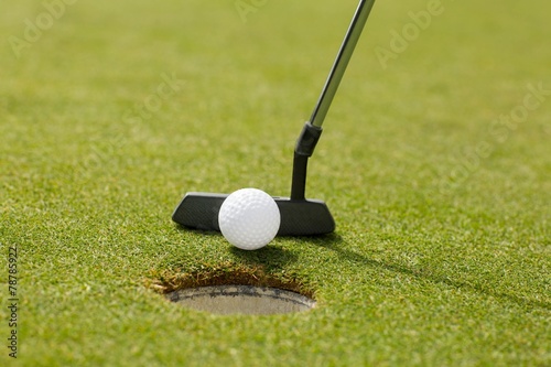 Golf club putting ball at the hole