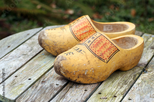 pair of traditional Dutch yellow wooden shoes on a wooden table