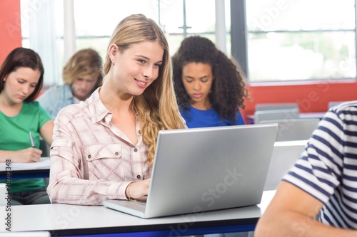 Female student using laptop in classroom