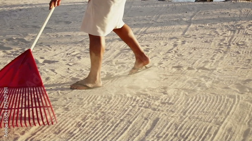 Beach attendant rakes the sand to clean the beach for tourists