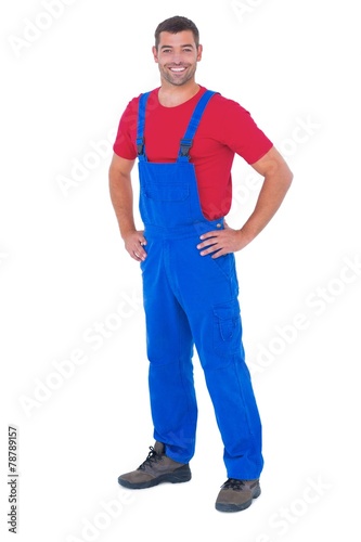 Happy handyman in overalls with hands on hip