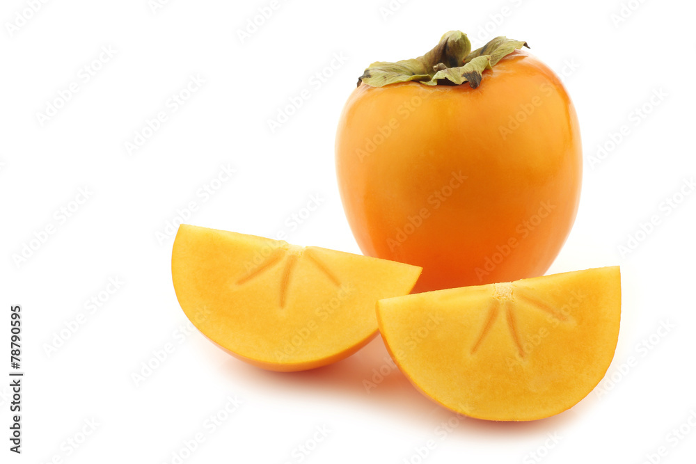 fresh kaki fruit and some cut pieces on a white background