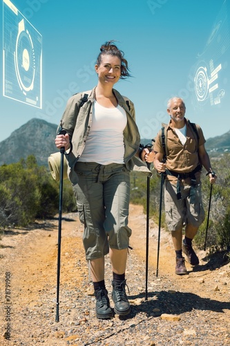 Composite image of happy hiking couple walking on mountain trail