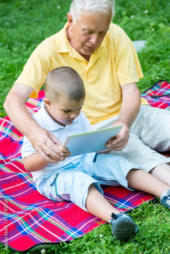 grandfather and child in park using tablet © .shock
