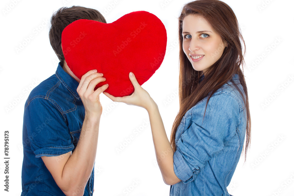 Beautiful young happy couple kissing behind a red heart Beautiful young happy couple kissing behind a red heart