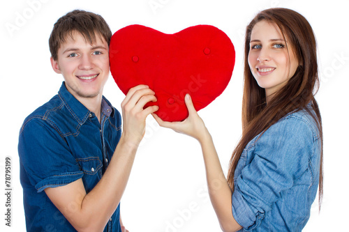 Beautiful young happy couple kissing behind a red heart