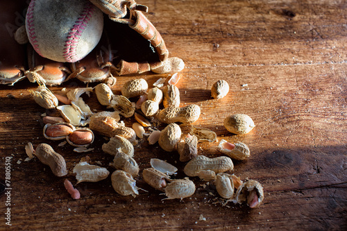 Peanuts in broken shells next to an old baseball glove and ball