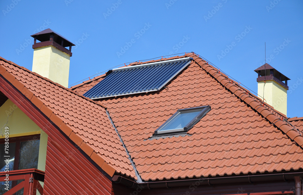 Solar water panel heating on house roof against blue sky