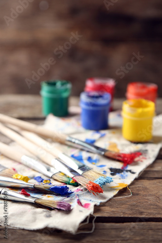 Brushes with colorful paints on old wooden background