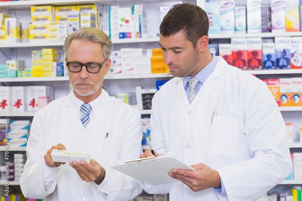 Team of pharmacists looking at medicine box Team of pharmacists looking at medicine box