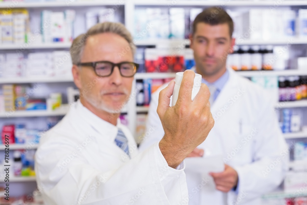 Pharmacist holding a box of pills while reading the label