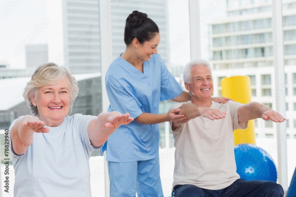 Trainer assisting senior couple in exercising Trainer assisting senior couple in exercising