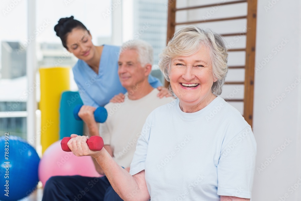 Senior woman lifting dumbbells while sitting with man Senior woman lifting dumbbells while sitting with man