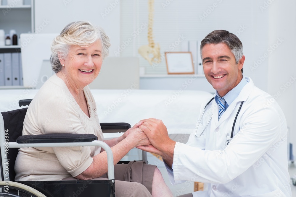 Fototapeta premium Happy doctor holding senior patients hands