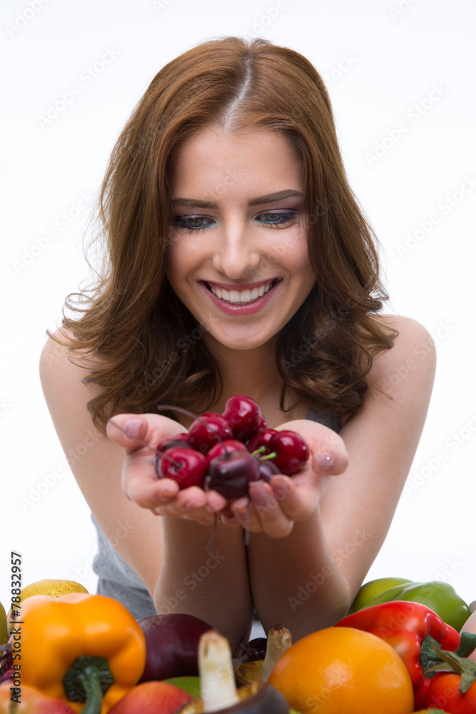 Smiling woman holding cherry over white background Smiling woman holding cherry over white background