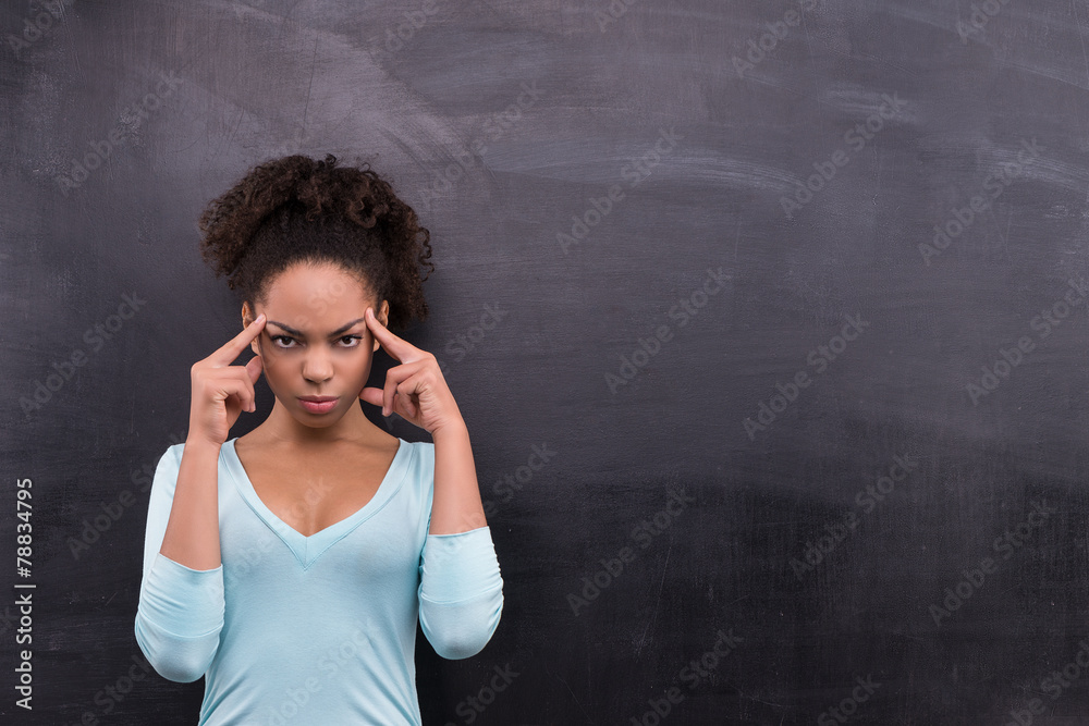 Thoughtful afro-american woman standing near chalkboard Thoughtful afro-american woman standing near chalkboard