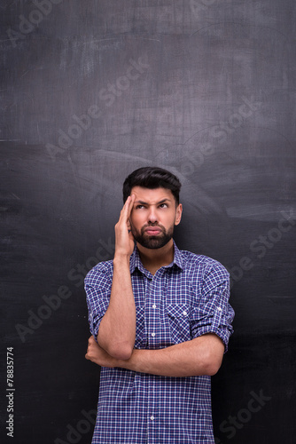 Dissatisfied casual man is on blank chalkboard background