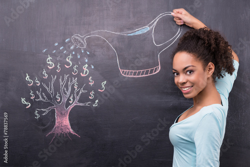 Young afro-american woman watering dollar tree painted on photo