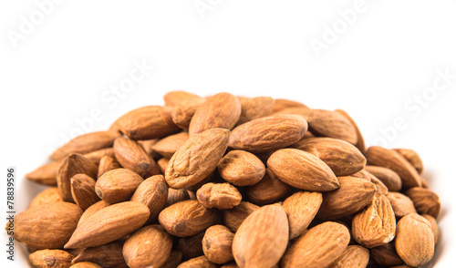 Raw almond nut in a white bowl over white background