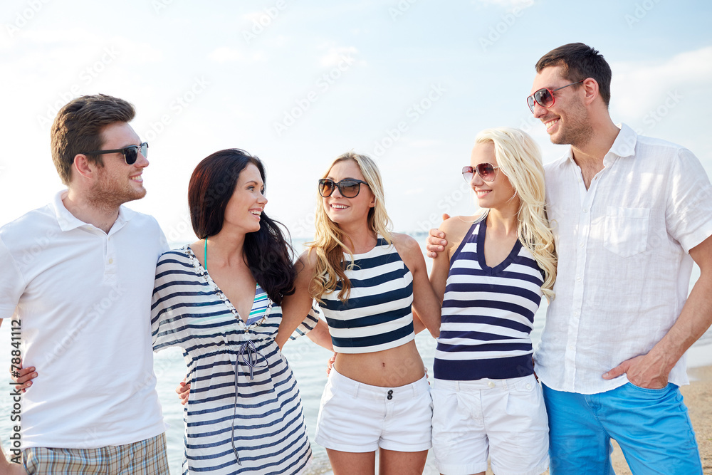 Fototapeta premium smiling friends in sunglasses talking on beach