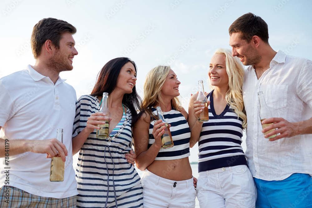 smiling friends with drinks in bottles on beach smiling friends with drinks in bottles on beach
