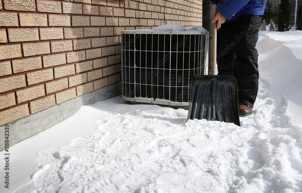 Man shoveling the show with AC on background Man shoveling the show with AC on background