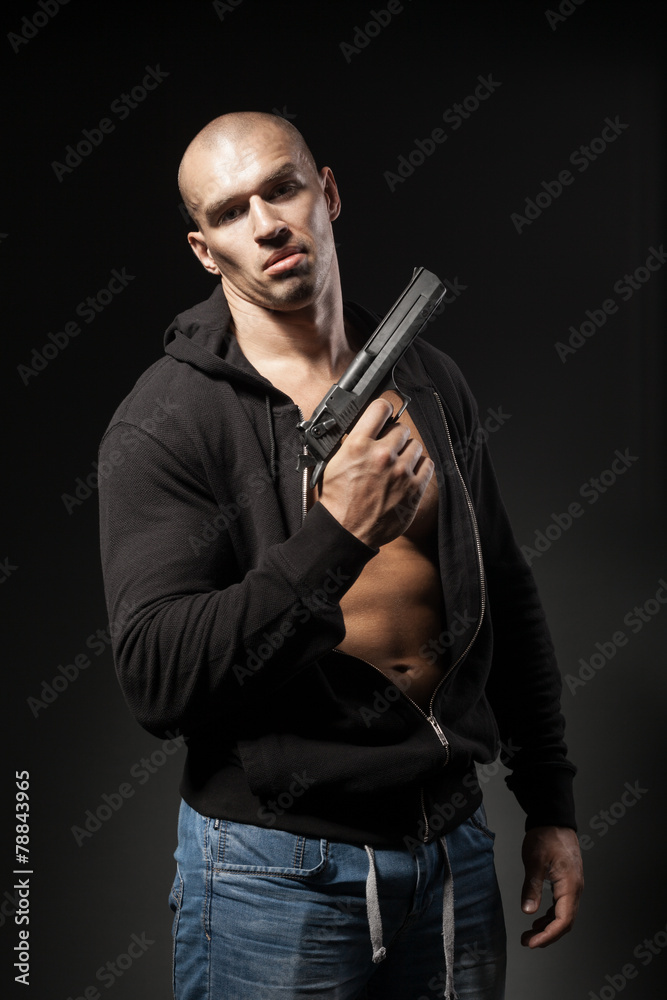 male gangster holding a gun isolated on dark background male gangster holding a gun isolated on dark background