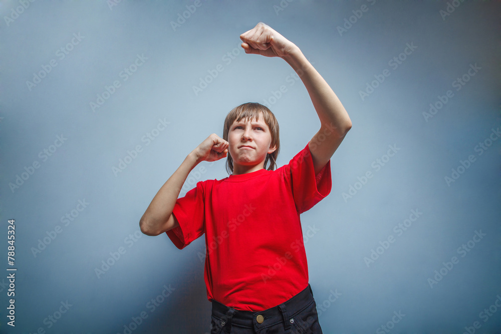 Boy, teenager, twelve years red in shirt, showing his fists Boy, teenager, twelve years red in shirt, showing his fists