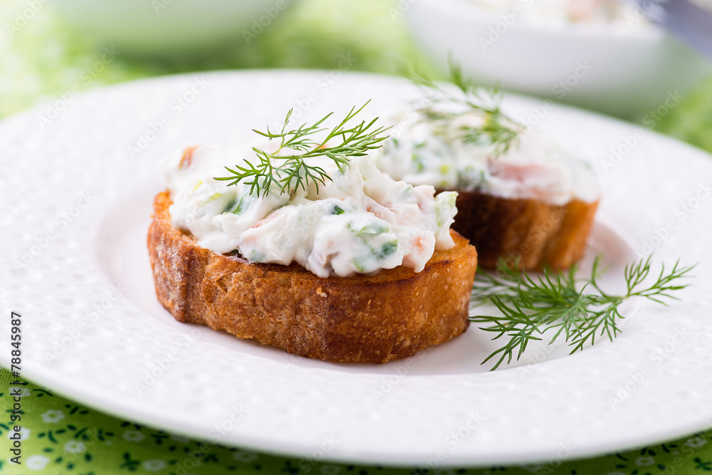 Canape with soft cheese spread on white plate