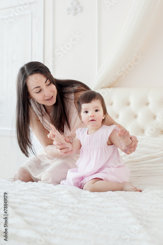 Young mother with little daughter in the bedroom