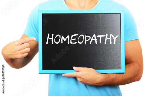 Man holding blackboard in hands and pointing the word HOMEOPATHY
