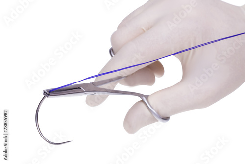 steel surgical  forceps  holding a suture needle photo