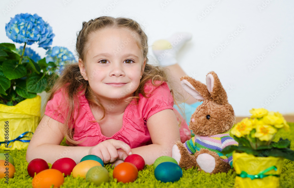 Smiling little girl lying with Easter eggs and flowers on green Smiling little girl lying with Easter eggs and flowers on green