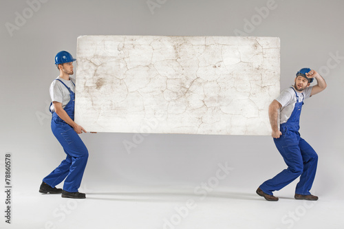 Photos Two workers carrying crashed banner