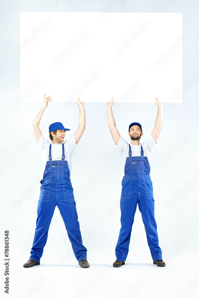 Obraz premium Two handsome builders holding a board