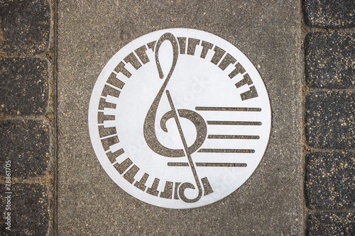 metal circle with a treble clef mounted into the stone pavement
