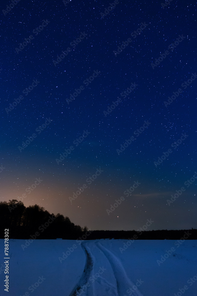 Naklejka premium Snow-covered road on the background of the starry night sky.
