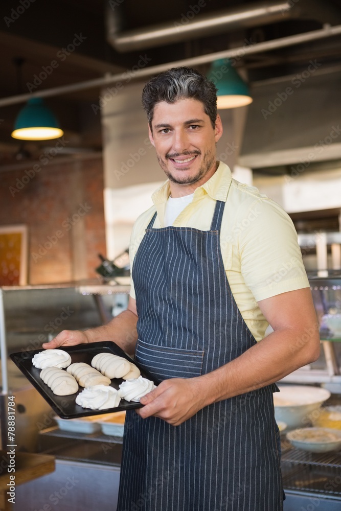 Smiling worker in apron holding tray of meringue Smiling worker in apron holding tray of meringue