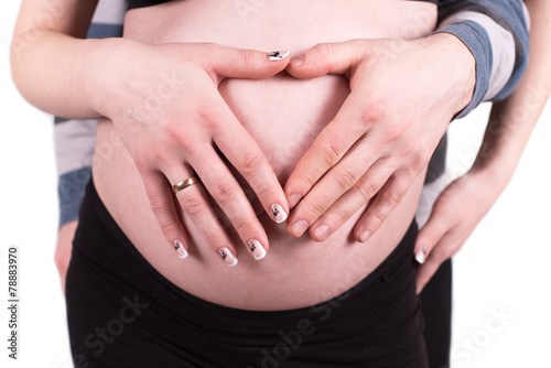Heart shaped hands of pregnant woman and her husband
