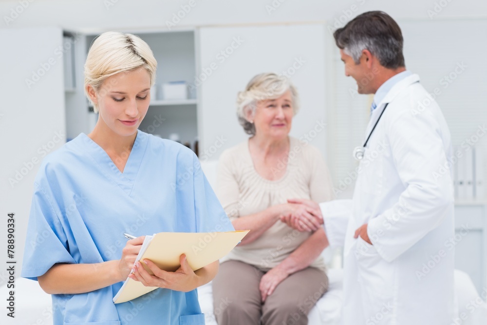 Female nurse making reports while doctor and patient talking