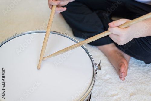 Boy teenager playing drums in room