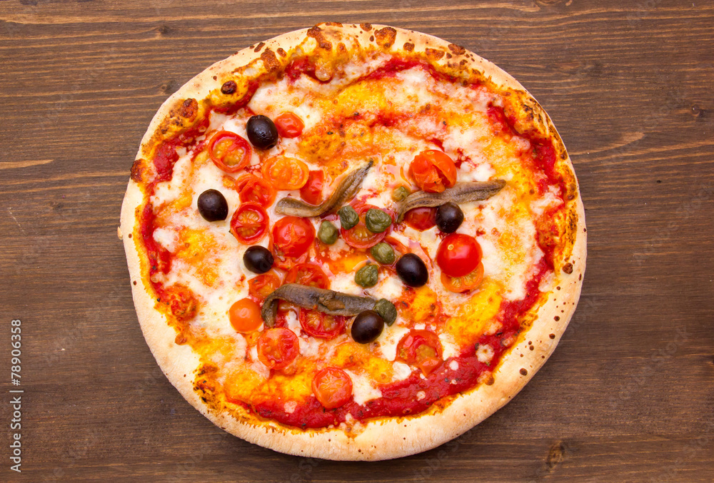 Pizza with anchovies and olives on a wooden table top view