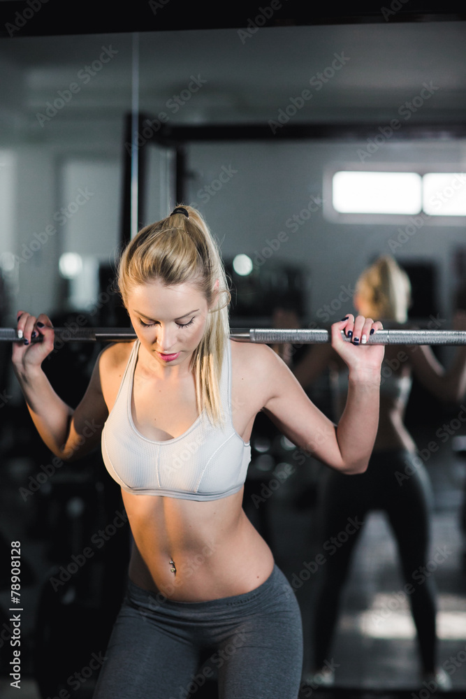 Girl doing exercise with barbell in gym