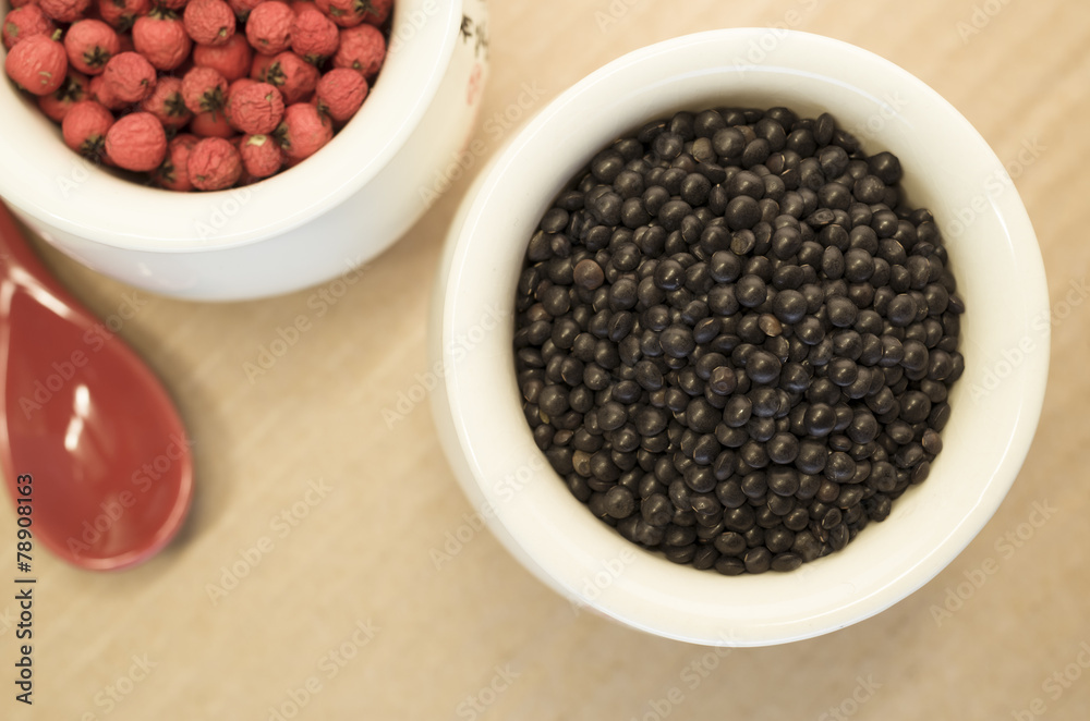 black lentils and red berries in a porcelain cup close up black lentils and red berries in a porcelain cup close up