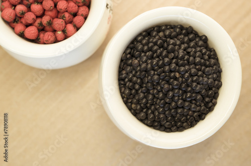 black lentils and red berries in a porcelain cup close up