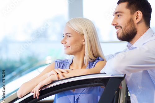 happy couple buying car in auto show or salon